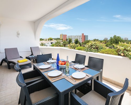 Balcony with outdoor dining and chaise lounge chairs.