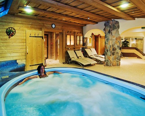 A girl in an indoor hot tub with chaise lounge chairs.