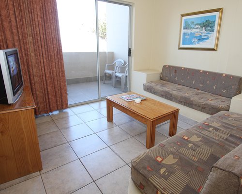 A well furnished living room with a television balcony and patio chairs.