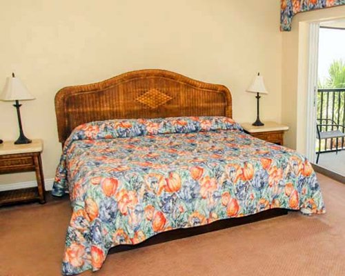 A well furnished bedroom with king bed and balcony.
