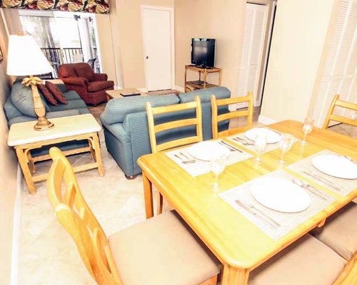 An open plan living room and dining area with a television and balcony.