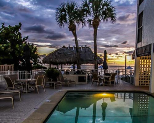 An outdoor swimming pool with dining area at dusk.