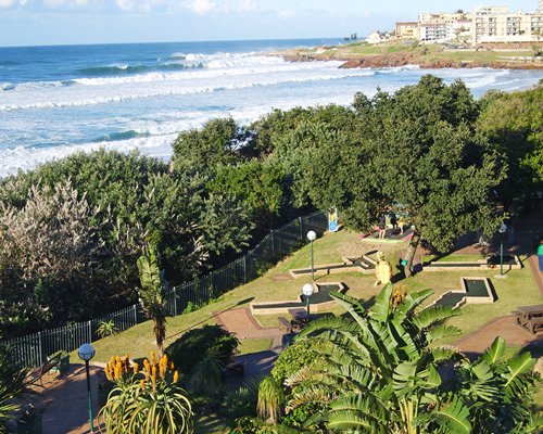 View of miniature golf courses surrounded by trees alongside the beach.