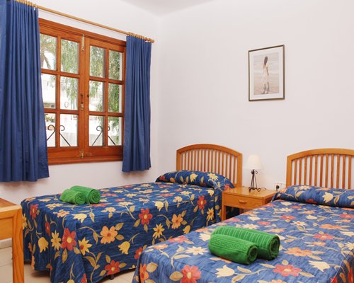 A well furnished bedroom with two twin beds and outside view.