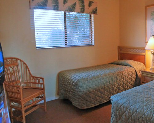 A well furnished bedroom with two twin beds television and outside view.