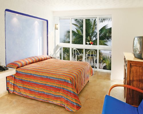 A well furnished bedroom with a television and balcony.