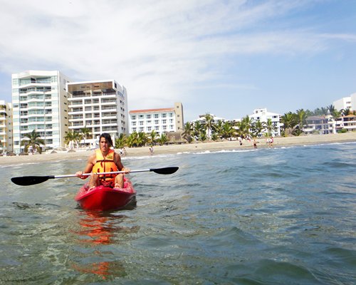 A woman on a sailboat in the ocean alongside the resort unit.