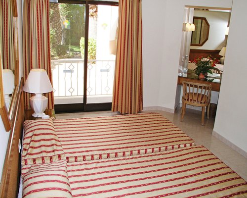 A well furnished bedroom with two beds mirror and an outside view.