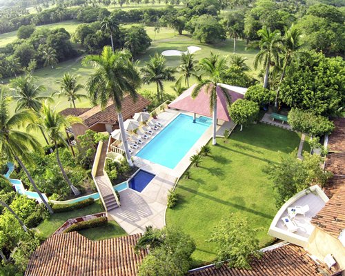 An aerial view of outdoor swimming pool with chaise lounge chairs and sunshades.