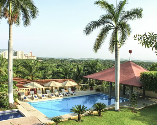 Outdoor swimming pool with chaise lounge chairs and sunshades.
