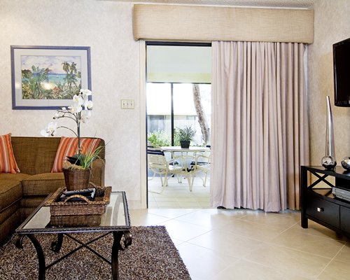 A well furnished living room with a television and balcony with patio furniture.