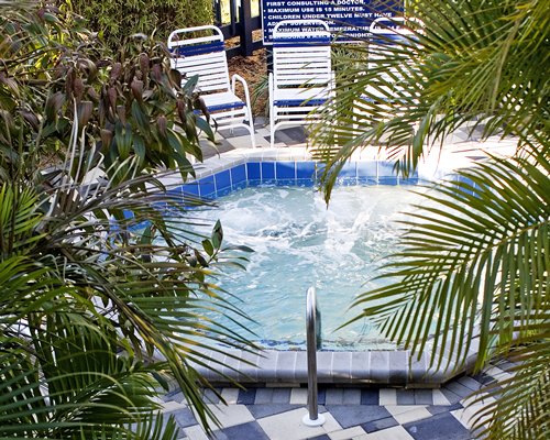 An outdoor hot tub with chaise lounge chairs.