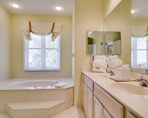 A bathroom with bathtub and double sink vanity.