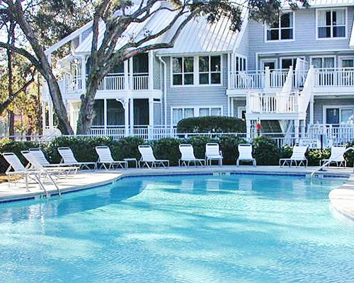 Outdoor swimming pool and chaise lounge chairs with the view of multiple balconies at Ocean Palms Resort.