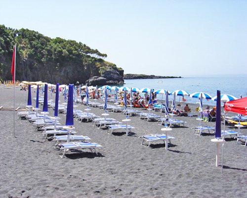 Chaise lounge chairs with sunshade in the coastal area of the ocean.