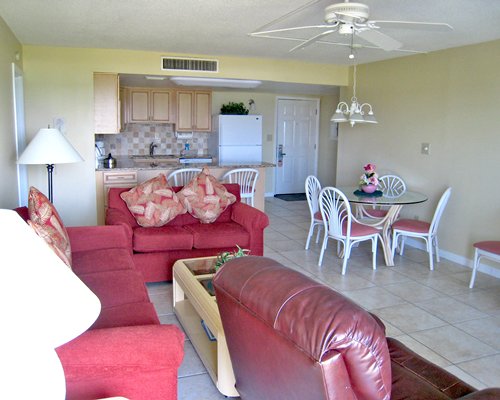An open plan living room with kitchen and glass top dining table.