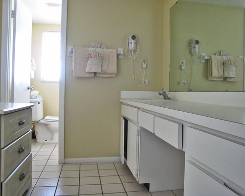A bathroom with an open sink vanity and dresser.