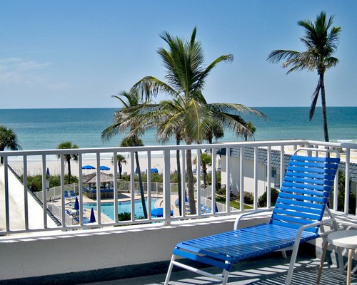 A balcony view of the ocean with a chaise lounge chair.