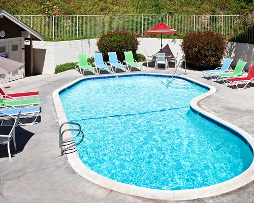 Outdoor swimming pool with chaise lounge chairs and sunshades.