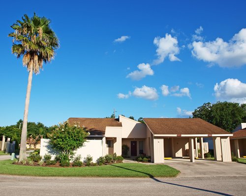 An exterior view of a resort units alongside a manicured lawn and palm trees.