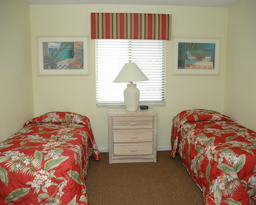A well furnished bedroom with a lamp and two beds.