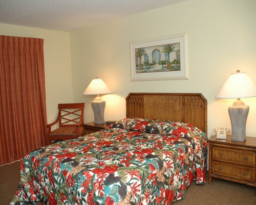 A well furnished bedroom with a queen bed and two lamps.