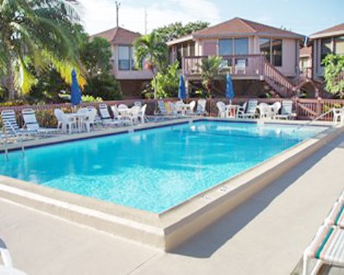 An outdoor swimming pool with chaise lounge and patio furniture alongside resort units.