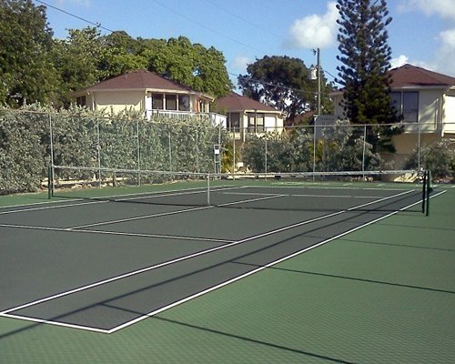 An outdoor tennis court surrounded by trees alongside resort units.