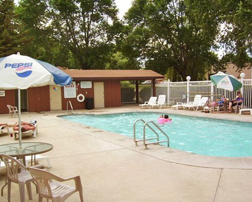An outdoor swimming pool with chaise lounge chairs surrounded by woods.