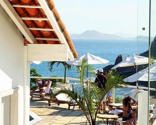 Outdoor patio with sunshades and chaise lounge chairs and ocean view.