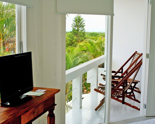A well furnished indoor room with a television and a balcony with patio furniture.