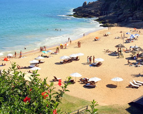 A beach with chaise lounge chairs and sunshades.