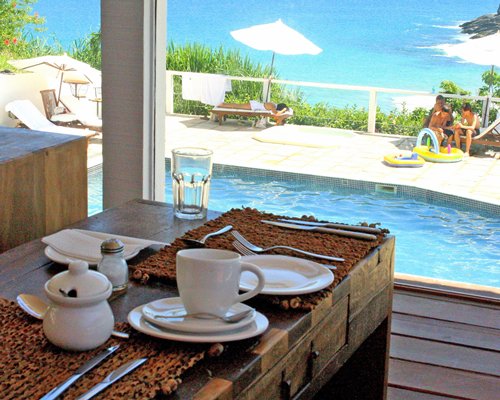 Outdoor swimming pool with chaise lounge chairs and sunshades alongside a snack bar.
