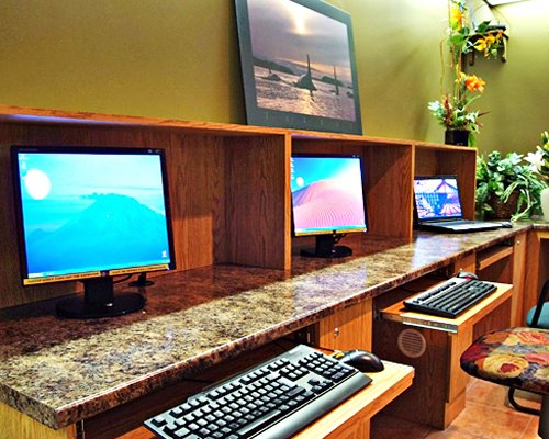 A common room with two computers and a laptop.