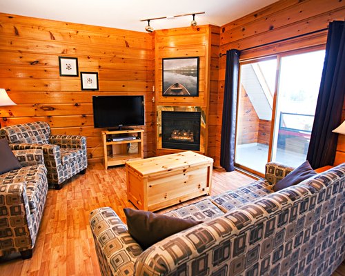 A well furnished living room with a television fire in the fireplace and balcony.