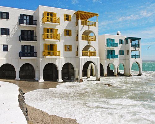 An exterior view of resort units with multiple balconies alongside the ocean.