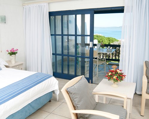 A well furnished bedroom alongside a balcony with patio furniture.