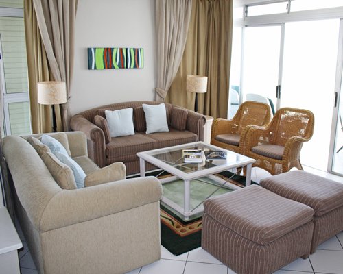 A well furnished living room with double pull out sofa and glass top teapoy.