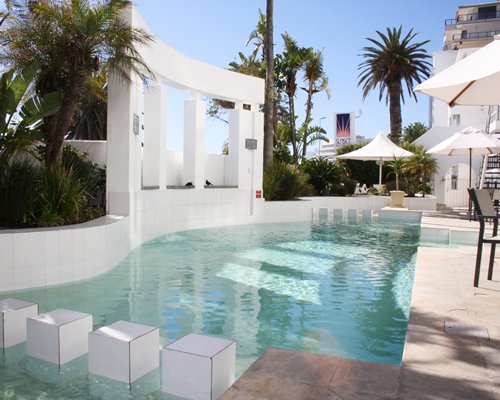 An outdoor swimming pool with thatched sunshades.