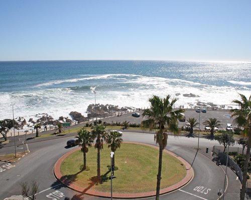 Scenic street view of The Peninsula All Suite Hotel with parking lot alongside the beach.