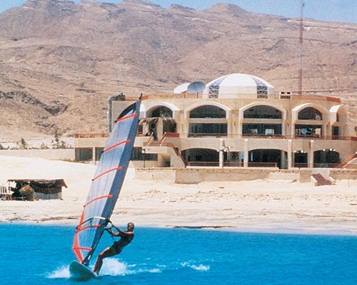 A man windsurfing on the water alongside the resort units.