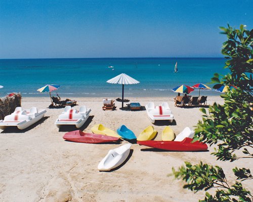 View of the beach with boats sunshades and chaise lounge chairs.