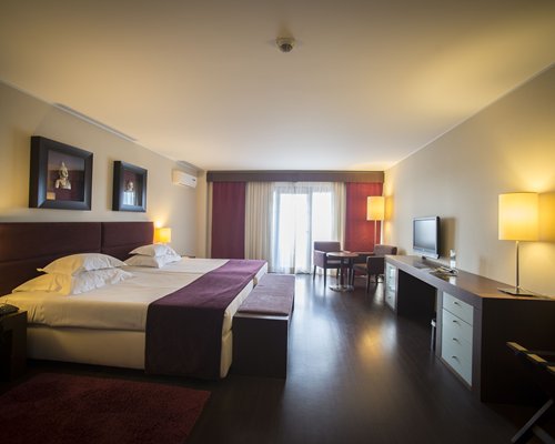 A well furnished bedroom with twin beds dining area and balcony.