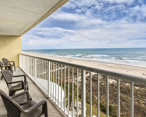 A balcony with patio chairs alongside the beach.