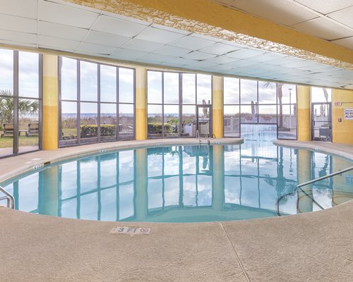 An indoor swimming pool with an outside view.