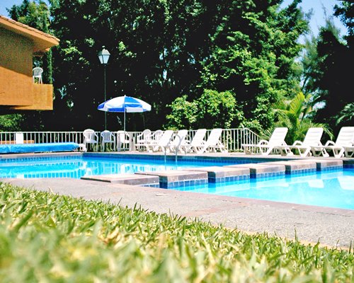 An outdoor swimming pool with chaise lounge chairs and sunshades.