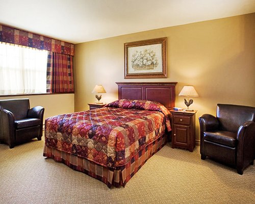 A well furnished bedroom with queen bed and an outside view.