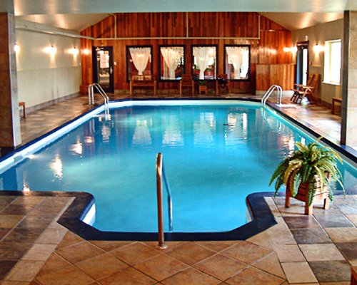 An indoor swimming pool alongside a well furnished area.