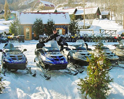 View of snowmobiles and the resort covered in snow.