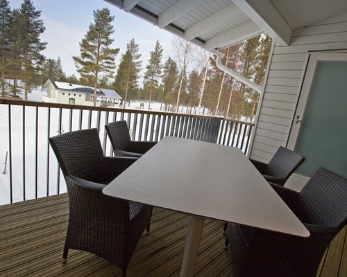 A balcony with patio furniture and a view of trees covered in snow.